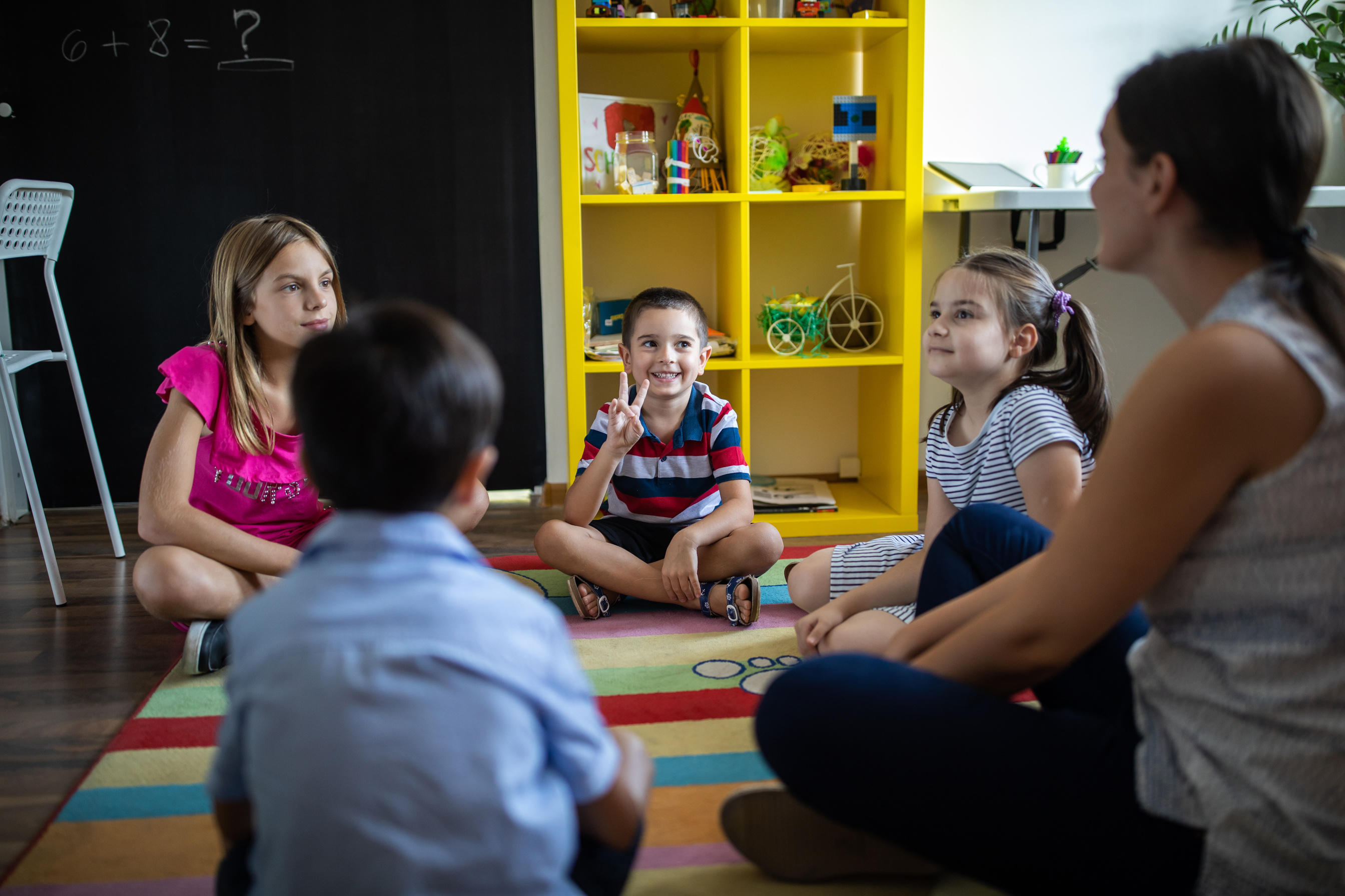 Female teacher and kids sitting at floor at childcare